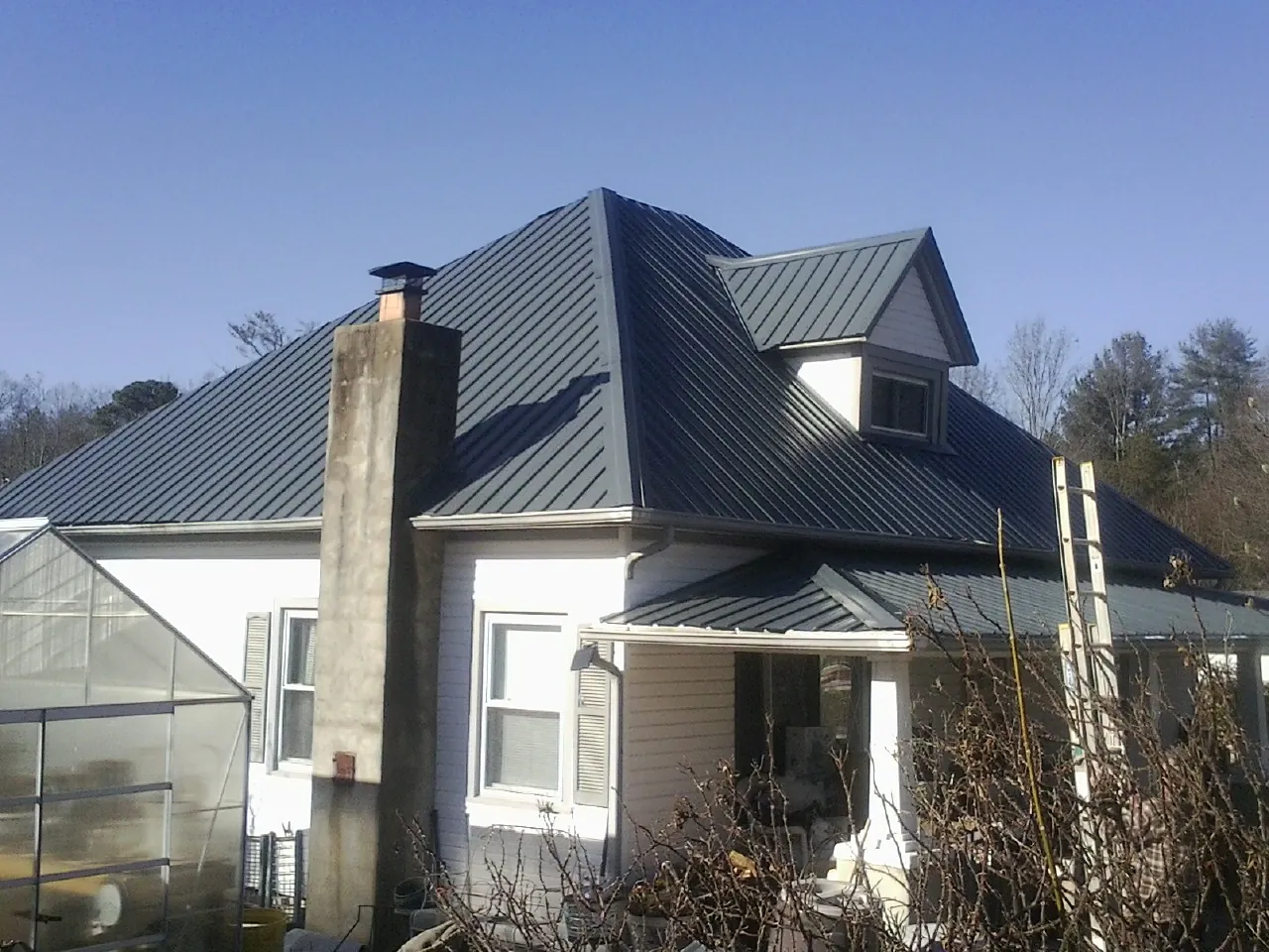 Dark blue standing seam metal roof on a white farmhouse with dormer — Slate & Tile Roof Repair by Roofing Brothers in Yorklyn