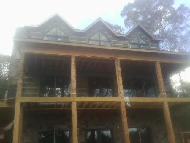 Dormers and porch framing on a large log home under construction — Roof Coating work by our crew in Yorklyn