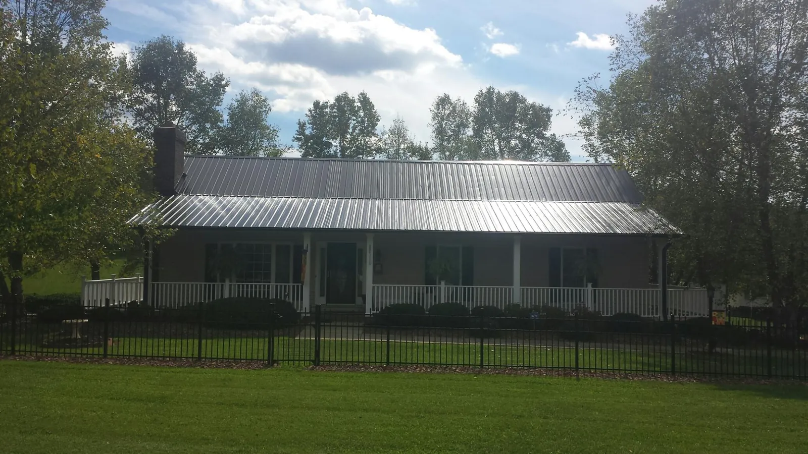Gray metal roof on a brick ranch with a full width front porch — Gutter Guard Installation work by our crew in Yorklyn