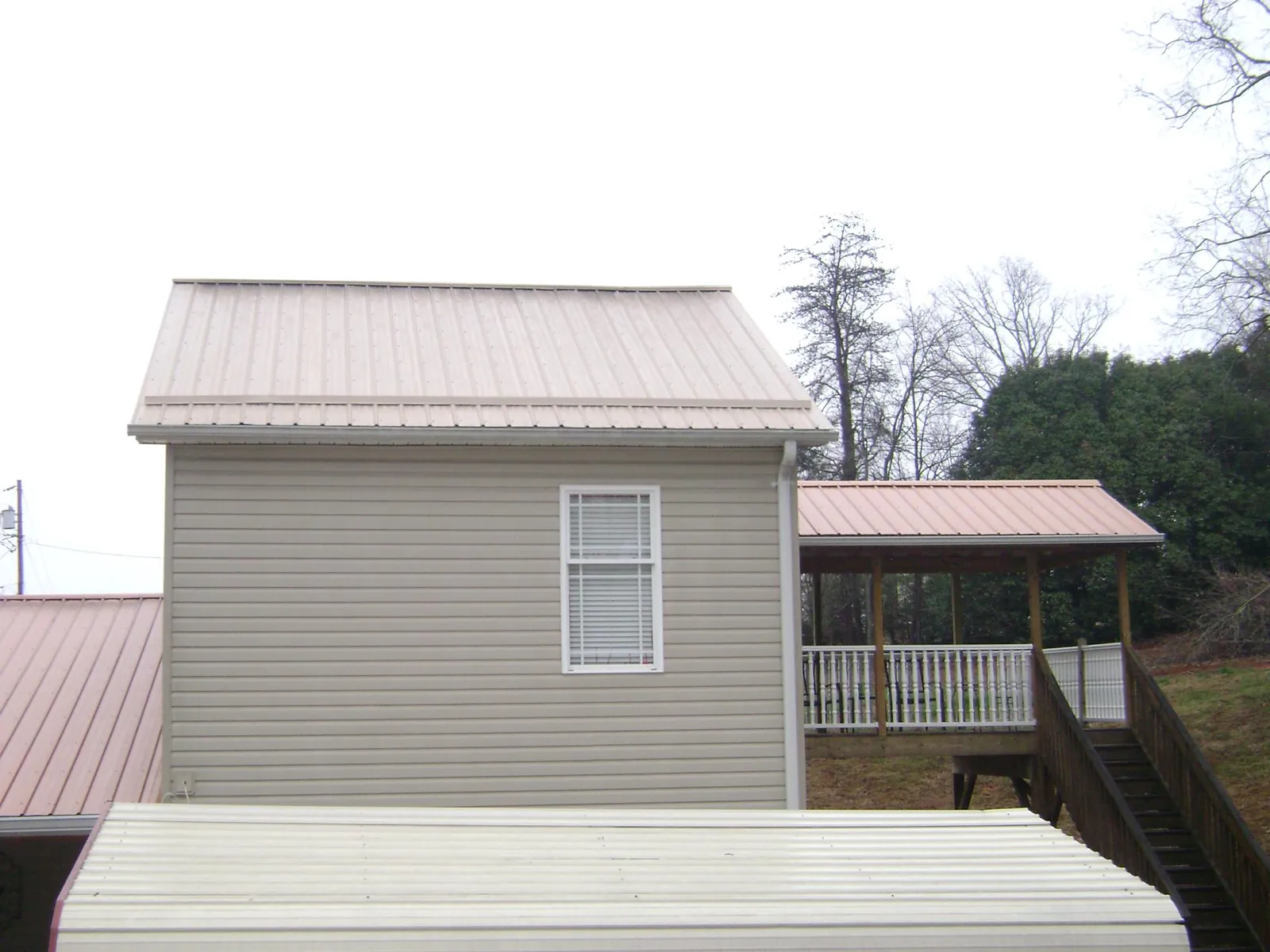 Tan metal roofs on a two story addition and attached porch, from a Roof Replacement job in Yorklyn